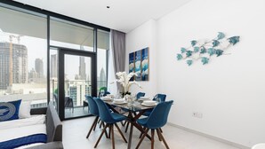 Un comedor moderno con una mesa de vidrio, sillas azules y vistas a la ciudad.