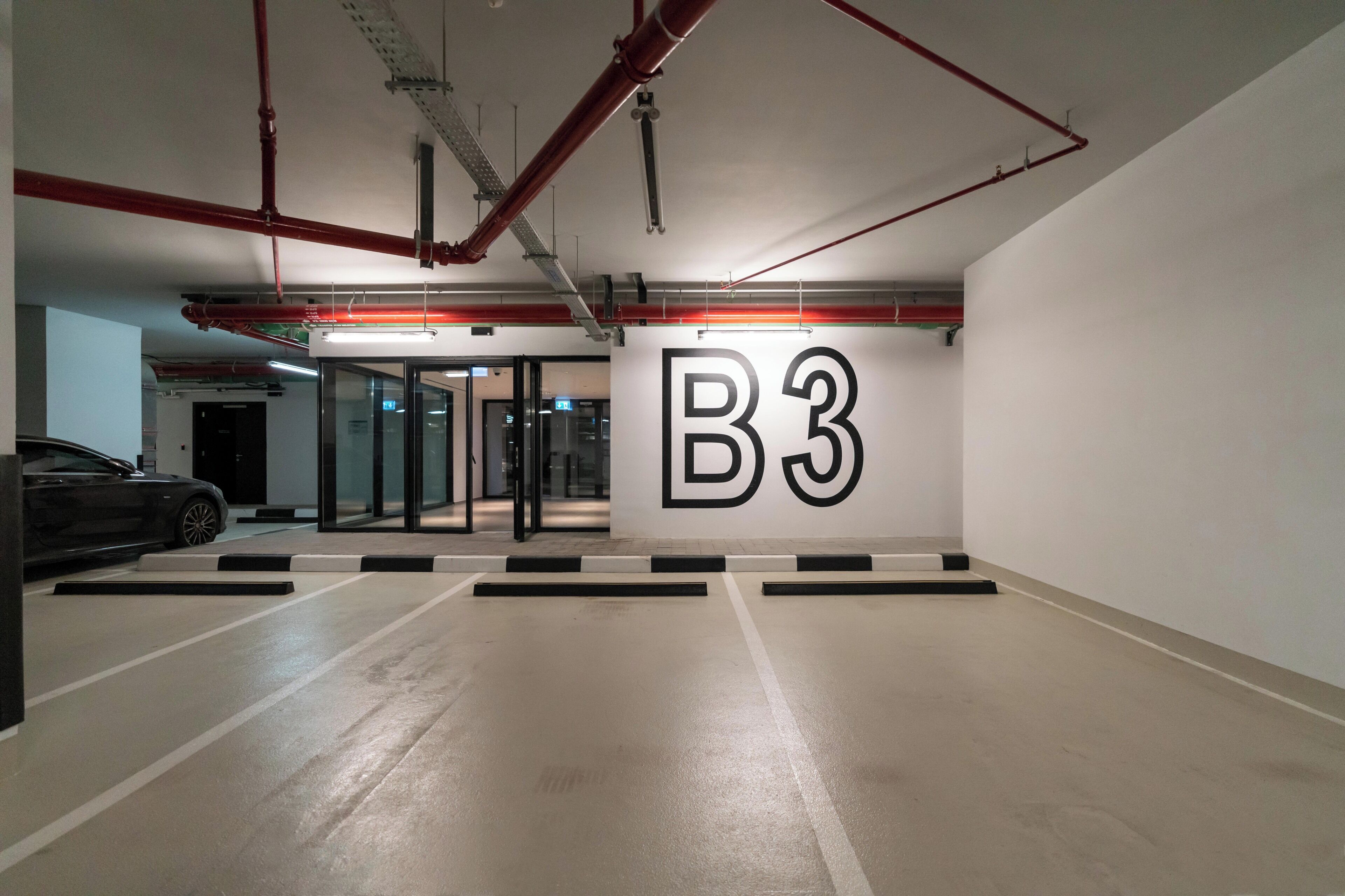Un parking souterrain avec une signalisation claire indiquant le niveau B3, de nombreuses places de stationnement et une voiture garée au loin.