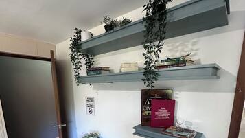 Una oficina en casa con escritorio, silla y estanterías llenas de libros y plantas decorativas.