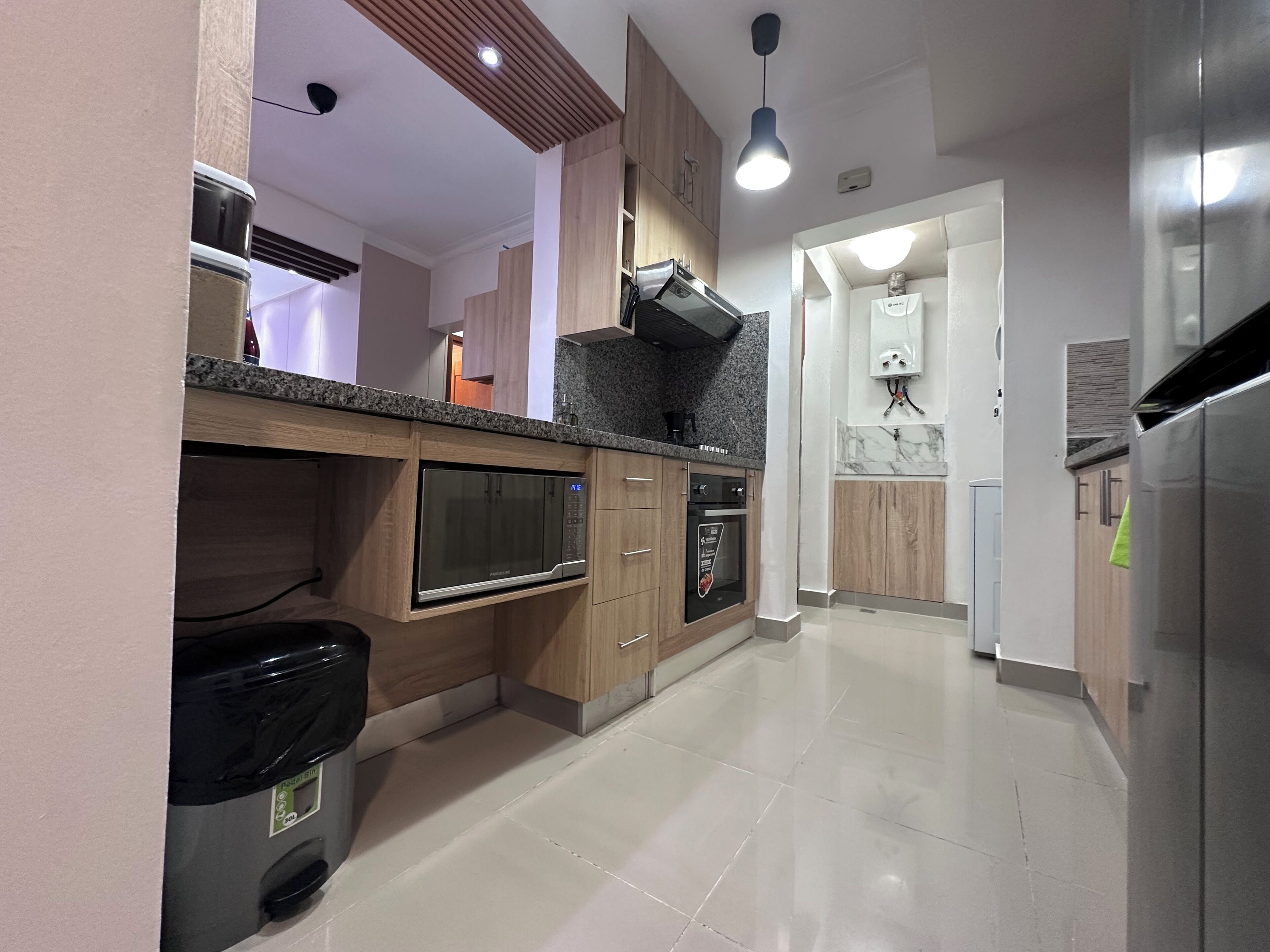 Una cocina moderna con electrodomésticos integrados, un cubo de basura y un piso de baldosas impecables.