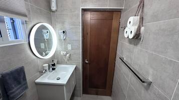 Un baño con lavamanos, espejo, toallero y retrete.
