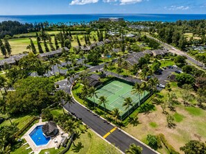 An aerial view of a resort with a tennis court, pool, and ocean views. - Beachside 4BR for 12, 2 Condos - Kuilima Estates! (Kahuku)