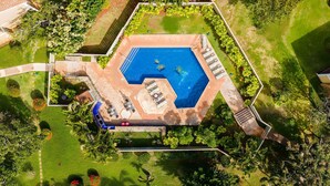 Vista aérea de uma piscina cercada por um jardim com área de varanda.