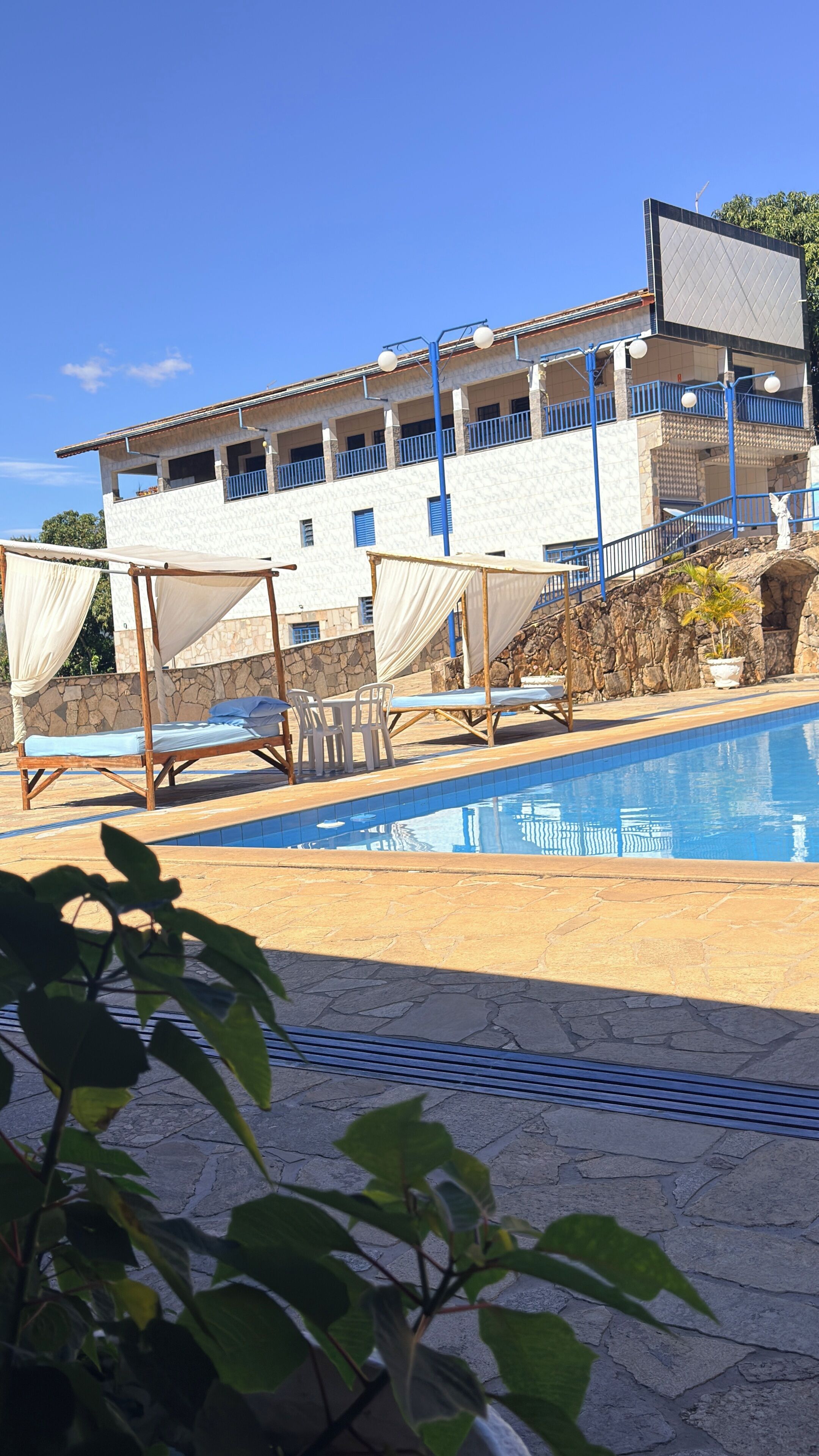 A pool area with lounge chairs and a building with balconies in the background.