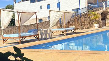 A pool area with lounge chairs and a building with balconies in the background.