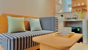 Una habitación moderna con un sofá a rayas, una mesa de madera y un espejo sobre una estantería con objetos decorativos.