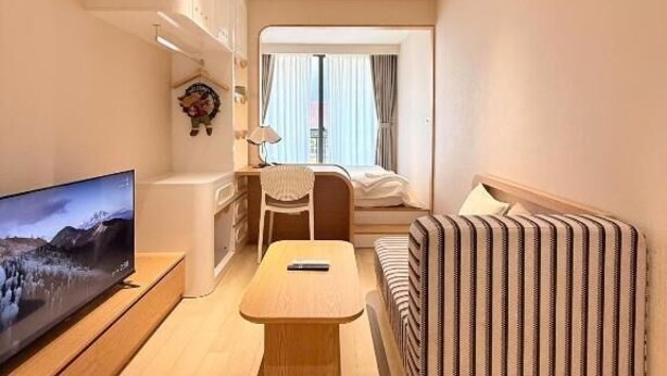 Una sala de estar moderna con un televisor de pantalla plana, un sofá, una mesa de centro y una pared decorativa a rayas.