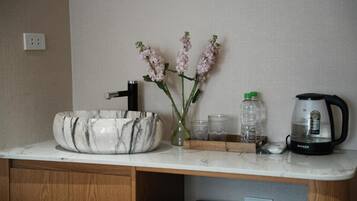 A kitchen counter with a marble sink, a coffee maker, and a vase with flowers.