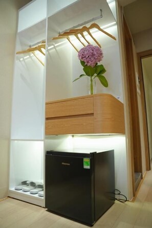 A compact kitchen with a black refrigerator, a wooden cabinet, and a hanging clothes rack. - D'la Lento Homestay (Hanoi)