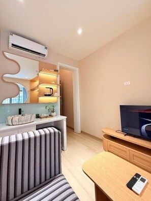 A modern living room with a sofa, a coffee table, a TV, and a built-in shelf unit. - D'la Lento Homestay (Hanoi)
