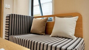 Una cama con ropa de cama a rayas y dos almohadas, un cabecero de madera y una ventana con persianas.