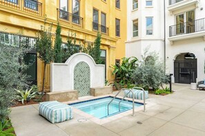 A courtyard with a swimming pool, surrounded by a yellow building and a white building. - Radiant King 1B1B｜Pool & Spa｜Smart 4K TVs (Montclair)