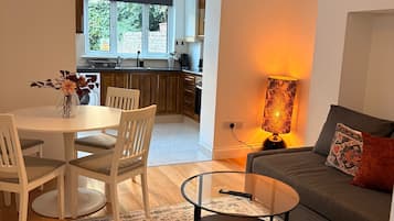 Una sala moderna con un sofá, una mesa de centro de vidrio y un comedor con sillas y una mesa.