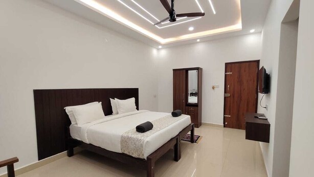 A modern bedroom with a bed, a wardrobe, a mirror, and a ceiling fan.