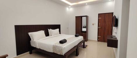 A modern bedroom with a bed, a wardrobe, a mirror, and a ceiling fan.