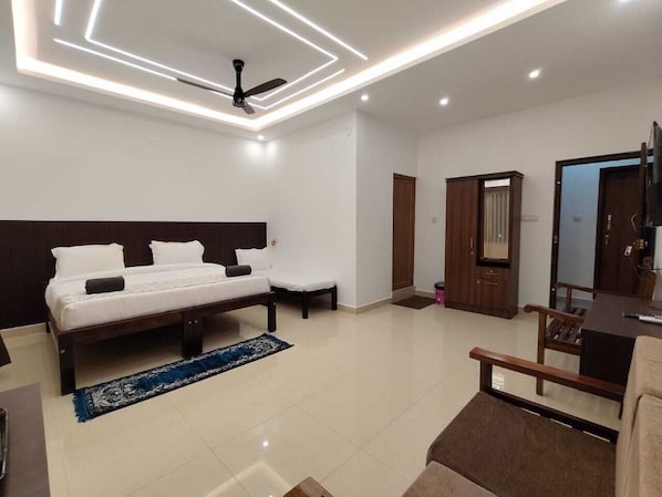 A modern hotel room with a bed, a desk, a chair, a ceiling fan, and a TV.