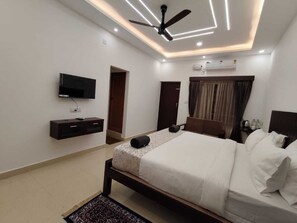 Una habitación de hotel moderna con cama, mesitas de noche, televisor y ventilador de techo.