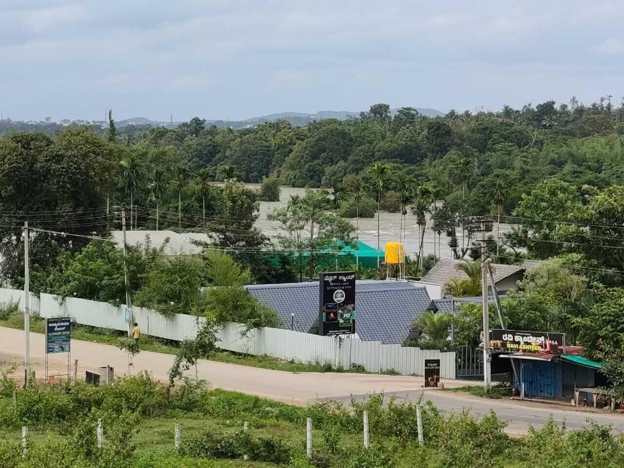 Zona rural con carretera, área cercada y edificio con paneles solares.
