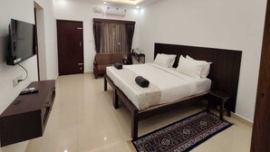 A modern hotel room with a bed, bedside table, TV, and a ceiling fan.