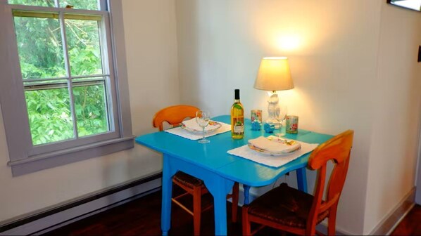 A dining table with chairs, a lamp, and a bottle of wine.