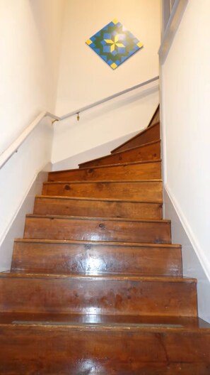A wooden staircase with white walls and a decorative tile on the wall above.