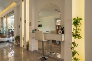 Um interior moderno com divisória de vidro, uma cadeira branca e um espelho.