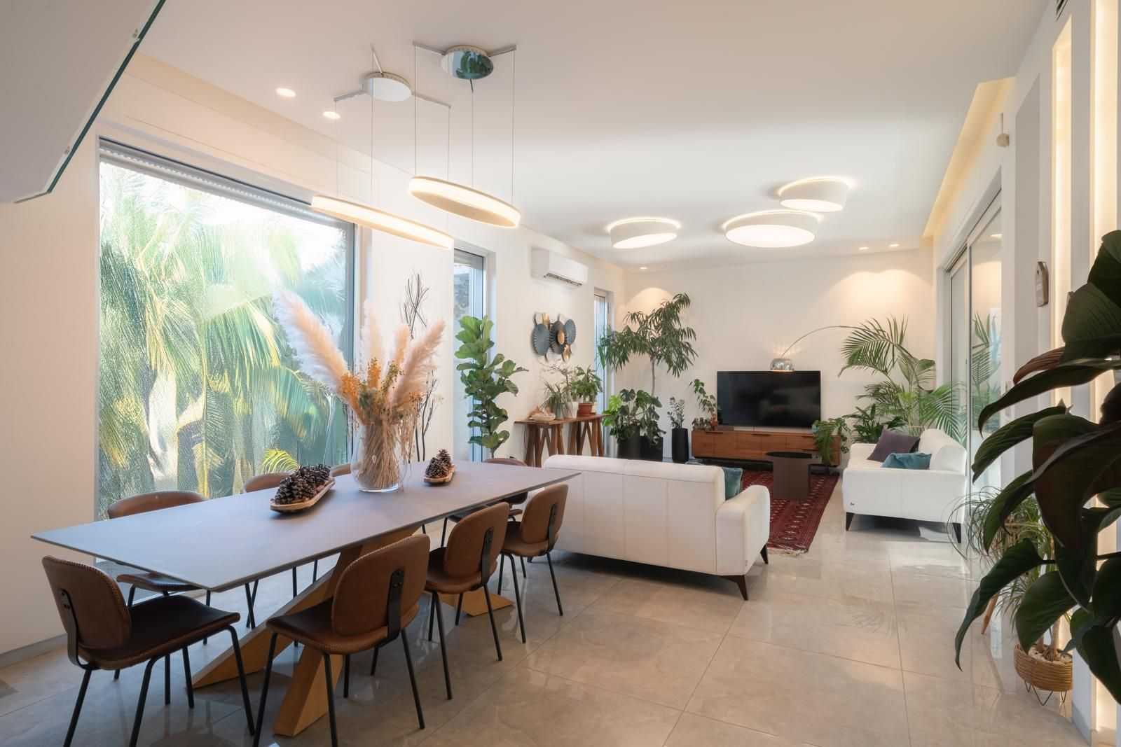 Una sala de estar moderna con comedor, ventanas amplias y un televisor de pantalla plana.