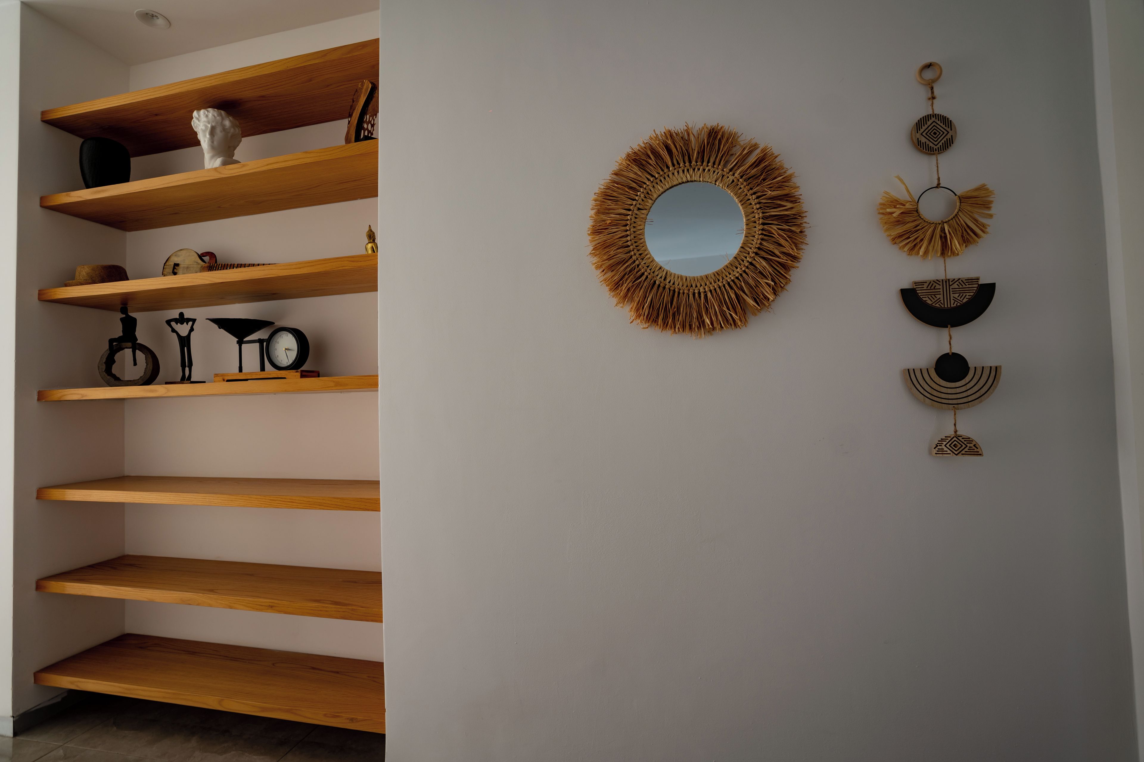 Une pièce dotée d'étagères en bois, d'un miroir rond et d'objets décoratifs fixés au mur.