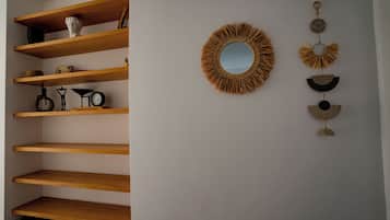 Une pièce dotée d'étagères en bois, d'un miroir rond et d'objets décoratifs fixés au mur.