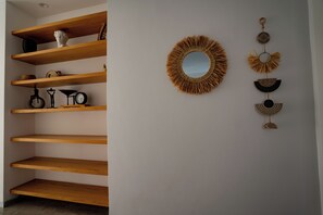 A room with wooden shelving units, a round mirror, and wall-mounted decorative items.