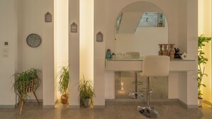 Un baño moderno con un espejo grande, un reloj y una barra con un taburete.