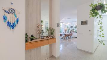 Un interior moderno con zona de comedor, un elemento decorativo en la pared y plantas en macetas.