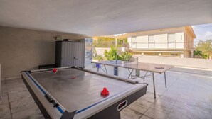 Una mesa de billar interior, una mesa de fútbol de mesa, una mesa de ping pong y un armario.
