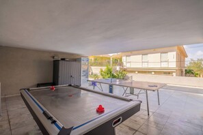 Mesa de bilhar interna com mesa de futebol de mesa, mesa de tênis de mesa e um armário.