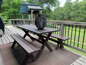 Eine Holzterrasse mit Picknicktischen und einer dekorativen Vase.