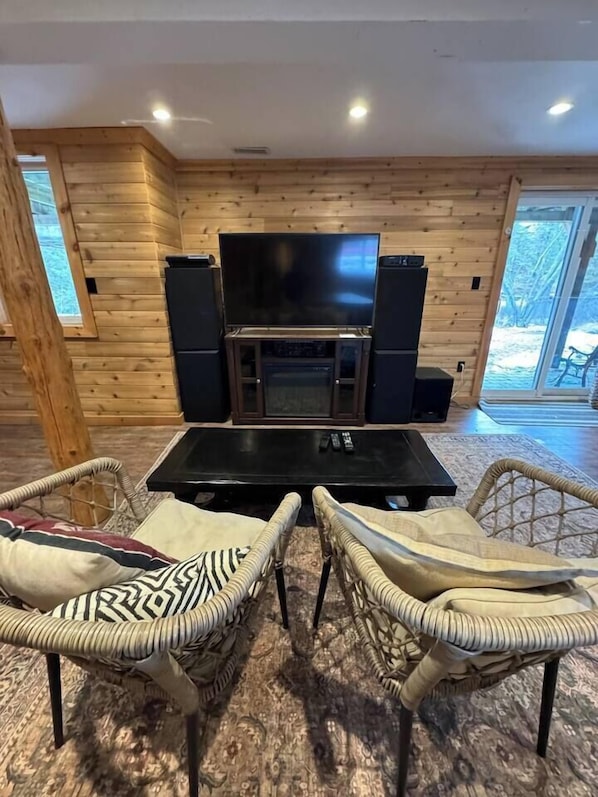 A cozy living area with a fireplace, a television, and wicker furniture.