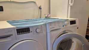 Eine Waschmaschine mit Frontlader, einer Selbstreinigungsfunktion, einer Bedienkonsole und einem Wasserzulaufschlauch.