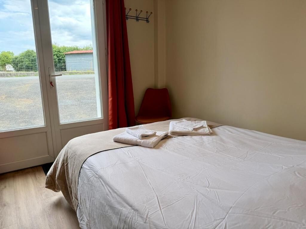 A hotel room with a bed, a window with curtains, and a view of the outside.