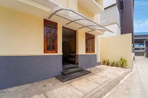 A residential building with a covered entrance, a staircase leading to the entrance, and a small garden area with potted plants. - Classic The Daffodils (Thiruvananthapuram)