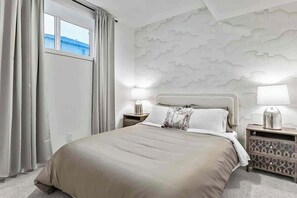 Ein Hotelzimmer mit einem Bett, zwei Nachttischen, einem Fenster mit Vorhängen und einer Wand mit strukturierter Gestaltung.