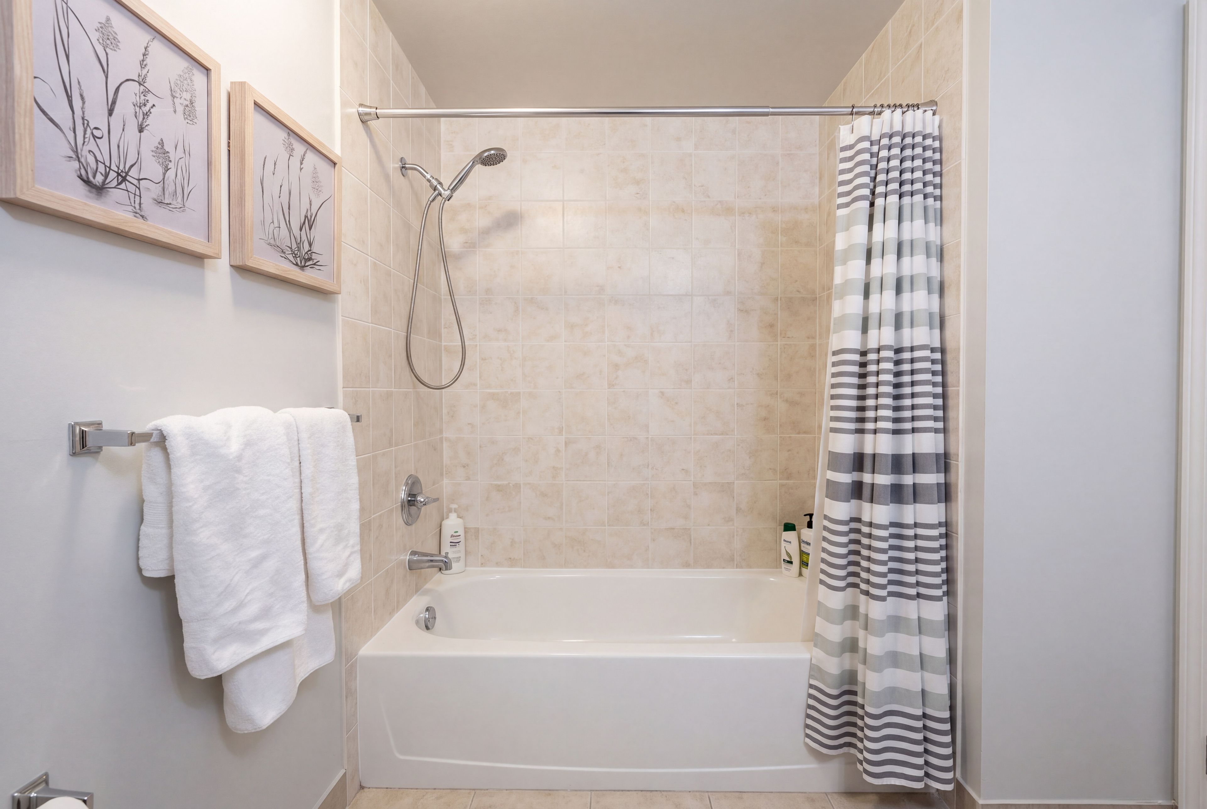 A bathroom with a bathtub, a shower, and a towel rack with two towels.