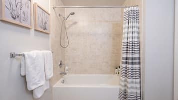 A bathroom with a bathtub, a shower, and a towel rack with two towels.