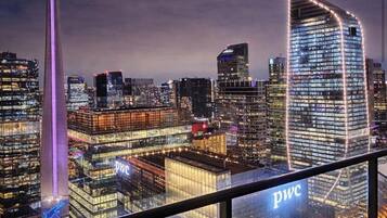 A cityscape with illuminated skyscrapers, including a prominent building with a curved facade and the 'PWC' logo.