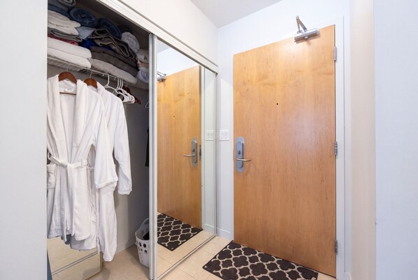 Un dressing où l'on peut entrer, avec des vêtements suspendus et des serviettes pliées.