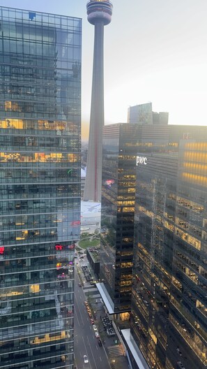 Une vue urbaine avec des immeubles modernes de grande hauteur, une tour imposante et une rue animée en contrebas.