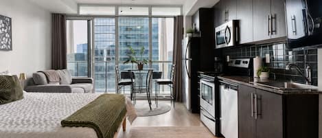 A modern apartment with a kitchenette, a dining area, and a bedroom.