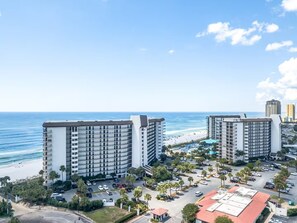 A high-rise hotel with multiple floors, a parking lot, and a beach view. - Beachfront Oasis at Edgewater Resort in Panama City Beach (Panama City)