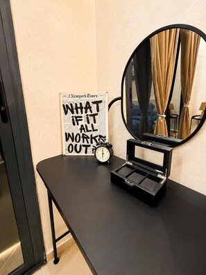 A room with a black vanity table, a round mirror, a clock, and a framed newspaper with a motivational quote. - Cozy&Chic Beach Apartment •Mohammedia el Mansouria (Mohammédia)