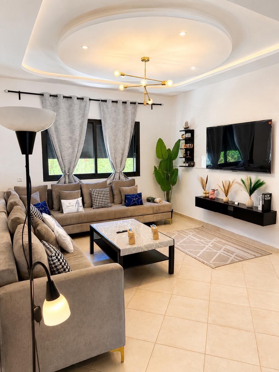 A modern living room with a sofa, coffee table, and a TV mounted on the wall.
