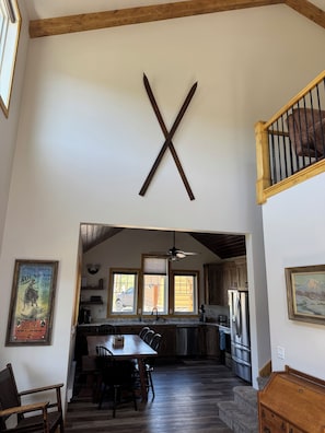 Une cuisine spacieuse avec des meubles de rangement en bois, un coin repas avec une table et des chaises, et un escalier menant à l’étage supérieur.